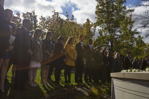 The 2015-16 Remembrance Scholars stand in front of the Wall of Remembrance during last year's Rose Laying Ceremony, which concludes the Remembrance Week events.